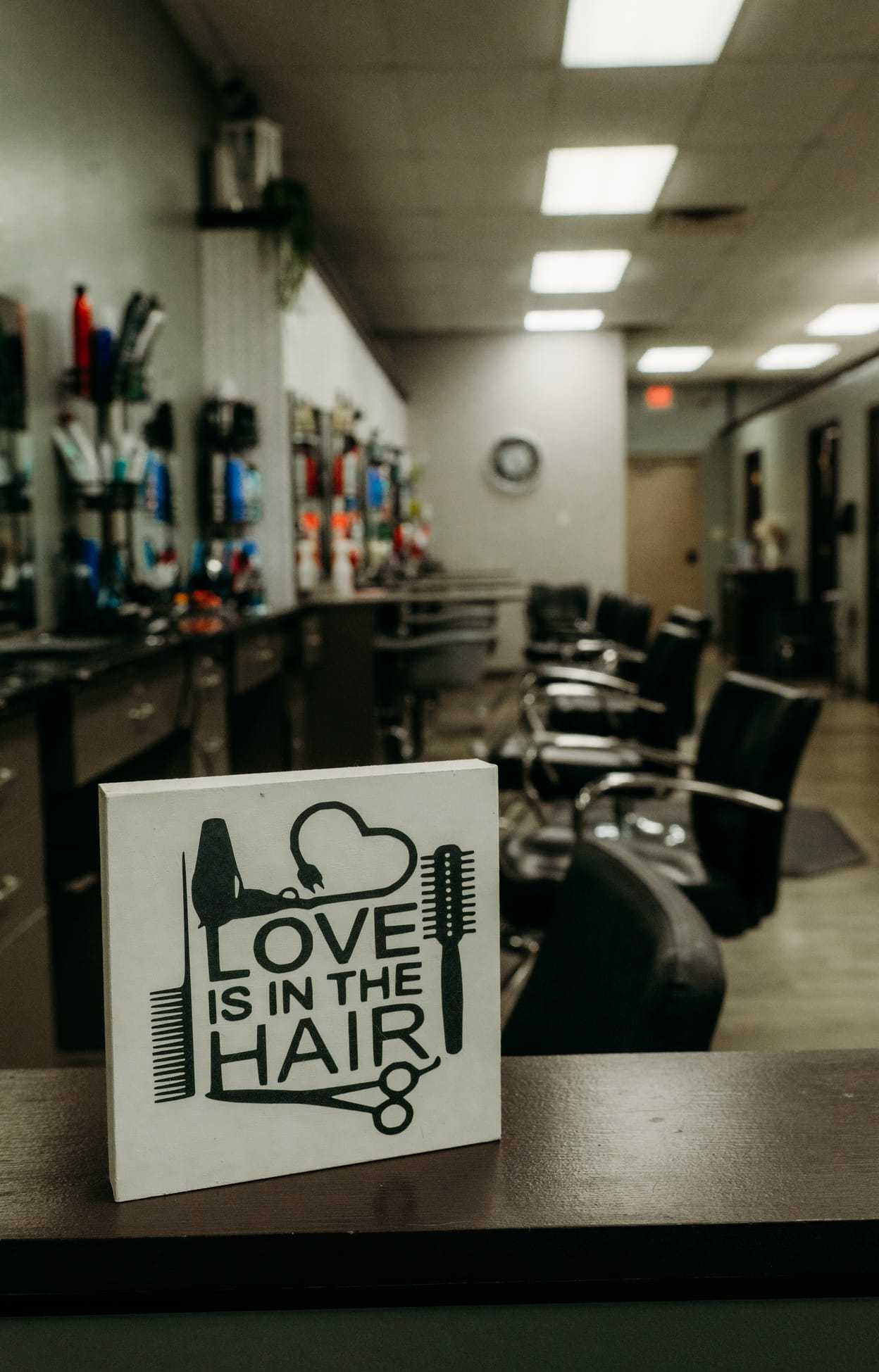 Salon interior with chairs, mirrors, and decor sign stating "Love is in the Hair".